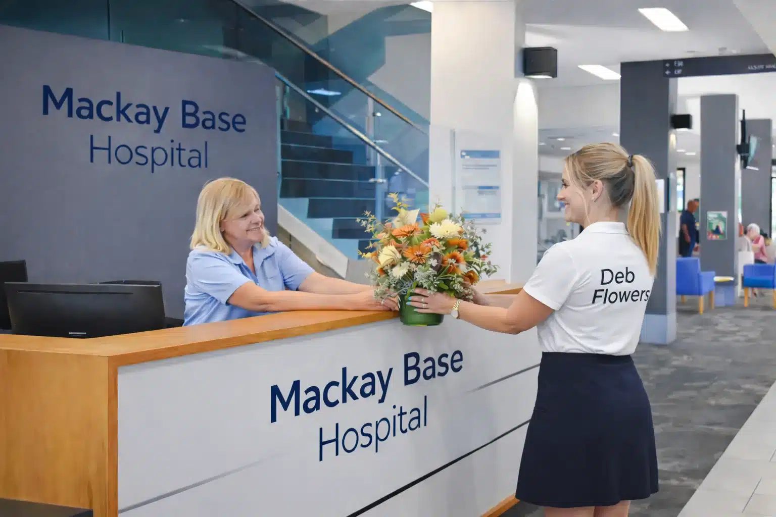 Deb Flowers delivery staff placing a vase of flowers on the reception desk at Mackay Base Hospital